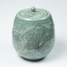 a green vase with floral designs on it