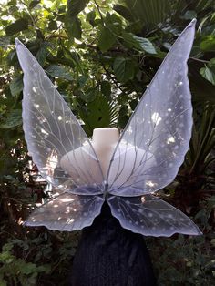 a white vase sitting on top of a black headdress in front of trees