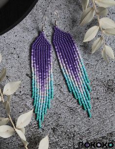 purple and green seed beaded earrings with leaves on the ground next to it's ear wires