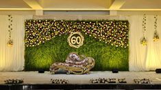 a stage set up with flowers and greenery on the wall, decorated with an old couch