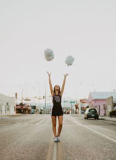 a woman is standing in the middle of an empty street holding pom - poms