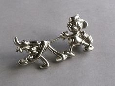 two silver figurines are holding hands on a gray surface, one is wearing a hat and the other has an umbrella