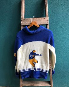 a blue and white sweater with a baseball player on it hanging from a wooden ladder