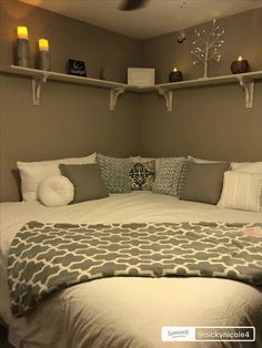 a bed with pillows and blankets on top of it in a room that has shelving above the bed