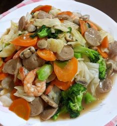 a white plate topped with vegetables and meat on top of a checkered table cloth