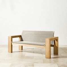 a wooden bench sitting on top of a tile floor next to a white wall in an empty room