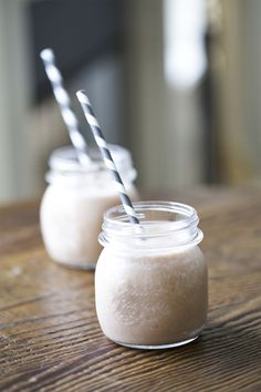 two mason jars with straws in them sitting on a table