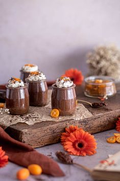 four desserts on a wooden board with flowers and oranges around them, sitting on a table