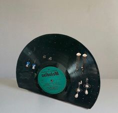 an old record with earring holder and jewelry on it's side, sitting on a white surface