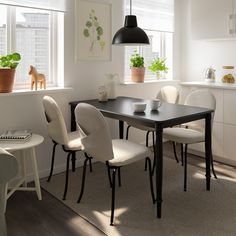 a dining room table with chairs and potted plants