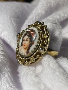 a ring with a picture of a woman on it sitting on top of a white blanket