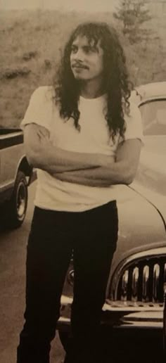 a man standing in front of a car with his arms crossed