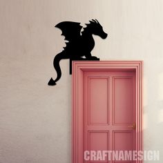 a black dragon on top of a pink door