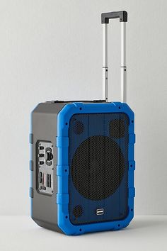 a blue and gray suitcase sitting on top of a white table next to a speaker