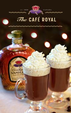 two glasses filled with hot chocolate and whipped cream on top of a table next to a bottle