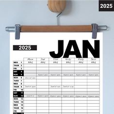 a printable calendar hanging on a wall next to a wooden hanger with clothes pins