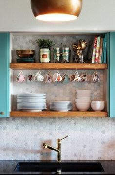 the shelves above the kitchen sink are filled with dishes