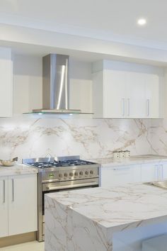 a kitchen with white cabinets and marble counter tops, stainless steel appliances and an oven