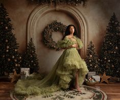 a woman in a green dress is posing for a christmas photo with her arms around her waist