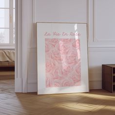 a white frame with pink roses on it in front of a wall that says la vie en rose