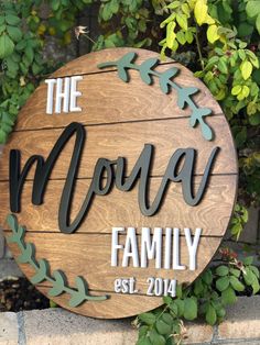 a wooden sign that says the mona family on it's side next to some plants