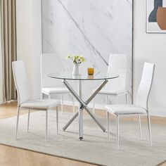 a glass dining table with white chairs and a vase on the top, in front of a marble wall