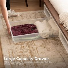 a woman is packing clothes in a drawer on the floor with her feet propped up