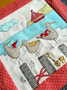 a close up of a piece of cloth on a table with a bird and boat