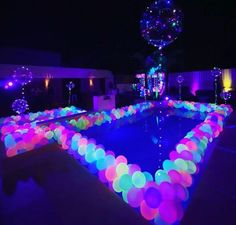 an illuminated pool with balloons floating in it