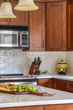 a kitchen with wooden cabinets and white counter tops, two hanging lights above the sink