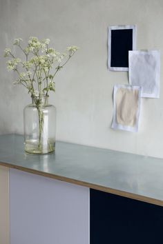 a vase filled with white flowers sitting on top of a counter next to a wall