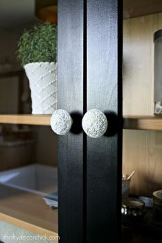 two white knobs are on the black cabinet door