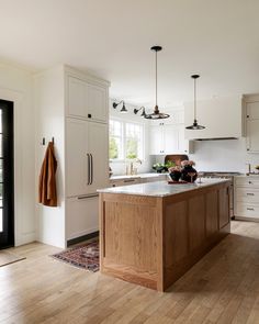 a large kitchen with white cabinets and wood flooring on the walls, along with an island in the middle