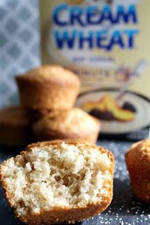 two muffins sitting on top of a table next to a bottle of cream