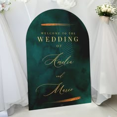 a green and gold wedding sign with white flowers