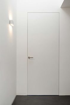 an empty room with a white door and two lights on the wall next to it