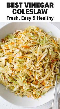 a white bowl filled with coleslaw on top of a table next to silverware