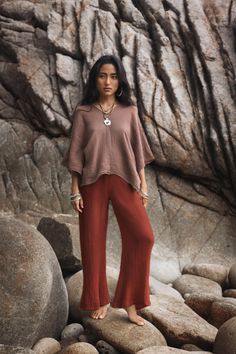 a woman is standing on some rocks