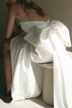 a woman in a white dress sitting on a toilet