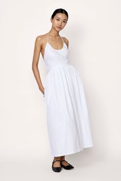 Embrace effortless elegance with our Halter Midi dress, designed for ease and style. Featuring delicate halter straps and intricate double elastic shirring throughout the back bodice, this dress ensures a flattering and comfortable fit. Crafted from soft organic cotton poplin, this mid-length dress includes practical side pockets, combining sophistication with functionality.Made with 100% organic cottonMachine wash cold, lay flat to dry.Handmade in India. Honoring Earth + Maker Our wovens are ha Sundress With Adjustable Straps And Halter Neck, Halter Neck Sundress With Adjustable Straps, White Ruched Back Maxi Dress For Summer, Spring Backless Dress With Ruched Bodice, White Backless Dress With Ruched Back For Spring, Summer Midi Dress With Adjustable Straps And Halter Neck, Halter Neck Maxi Sundress For Daywear, White Sleeveless Backless Dress With Ruched Back, Chic Midi Halter Dress For Daywear