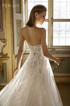 a woman in a wedding dress looking down at the back of her bridal gown