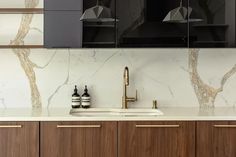 a kitchen with marble counter tops and wooden cabinetry, along with black cabinets that have brass pulls on them