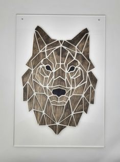 a wooden cutout of a wolf's head on display in a white frame