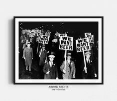 black and white photograph of men holding signs with we want beer written on them while walking down the street