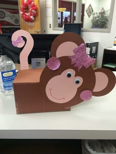 a cardboard box shaped like a monkey with pink glitter on its ears and tail sitting on a table