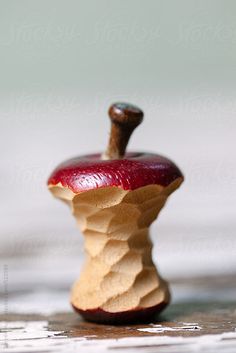 an apple that is sitting on top of a wooden table by some kind of object