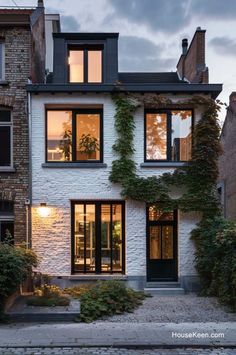 a white brick house with lots of windows and ivy growing up the side of it