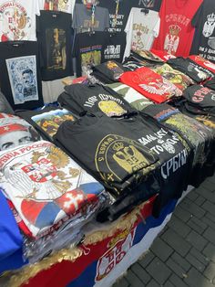 many shirts are on display at an outdoor market