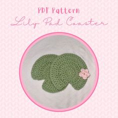 two green crocheted hats on top of a pink and white plate with the words pattern lily pad coaster