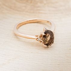 a close up of a ring with a brown diamond in it on a wooden surface